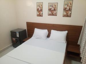 ein Bett mit weißen Laken und einem hölzernen Kopfteil in der Unterkunft Résidence Keur Mame Seye 3 in Dakar