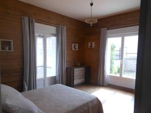Un dormitorio con una cama y dos grandes ventanales. en Gîte Le Rabelais, en Thésée 20 fotos más