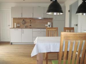 een keuken met een tafel, stoelen en zwarte lampen bij Urlaub bei Alma in Wurster Nordseeküste
