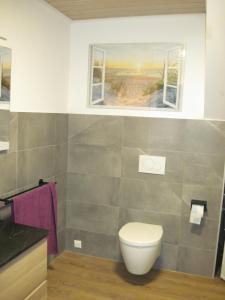 een badkamer met een toilet en 2 ramen bij Urlaub bei Alma in Wurster Nordseeküste