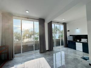 a living room with large glass windows and a kitchen at Turtle Bay Resort Hikkaduwa in Hikkaduwa