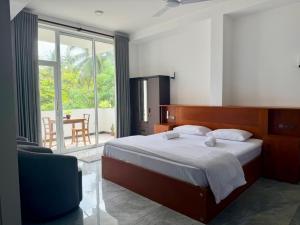 a bedroom with a large bed and a balcony at Turtle Bay Resort Hikkaduwa in Hikkaduwa