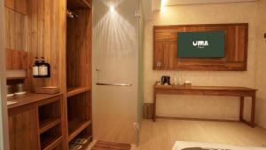 a bathroom with a shower with a tv on the wall at Uma Tilu By Seken Living in Yogyakarta +22 photos