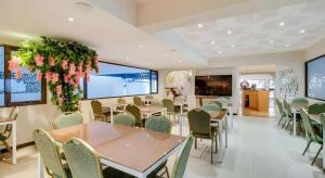 a dining room with tables and chairs and flowers at Mine Home Hotel by SOVIA in Bandung