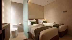 a hotel room with two beds and a bathroom at Uma Tilu By Seken Living in Yogyakarta