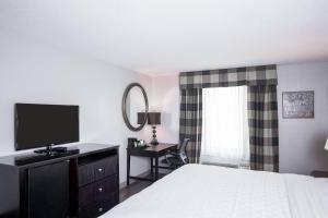a hotel room with a bed and a television at Carradoc Hall Hotel & Conference Center by The Red Collection in Leesburg