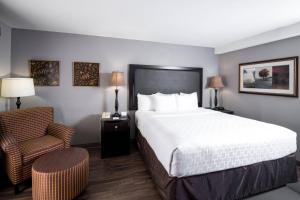 a hotel room with a large bed and a chair at Carradoc Hall Hotel & Conference Center by The Red Collection in Leesburg