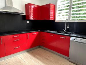 a kitchen with red cabinets and a sink at Kaz coco mango in Basse-Terre