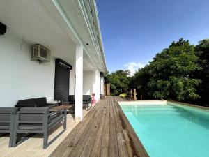 a swimming pool on a wooden deck next to a house at Kaz coco mango in Basse-Terre