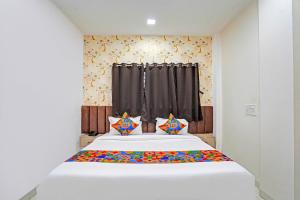 Un dormitorio con una gran cama blanca con almohadas de colores. en FabHotel Amrit Palace, en Indore