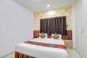 Un dormitorio con una gran cama blanca con almohadas de colores. en FabHotel Amrit Palace, en Indore