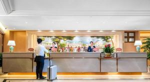 a man standing at a counter in a hotel lobby at Vienna Hotel Chongqing Wushan Municipal Government in Wushan