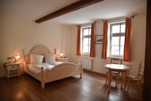a bedroom with a bed and a table and two windows at Altstadthotel Garni Schlundhaus & Rautenkranz in Meiningen