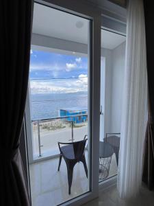 een kamer met een glazen schuifdeur en uitzicht op de oceaan bij Aluna Bay Hotel in Balige