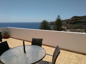 a glass table and chairs on a balcony with the ocean at Apartamentos Noda in Playa de Santiago
