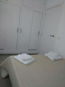 two white towels sitting on a bed in a room at Apartamentos Noda in Playa de Santiago