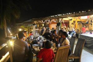 un grupo de personas sentadas en una mesa en un restaurante en 77 Sunset Plaza, en Karanghawu