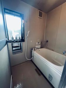 a bath tub in a bathroom with a window at 宿えんがわーおもや in Tokorozawa