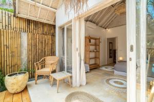 een kamer met een veranda met een bed en een stoel bij Villa Satu Cinta in Gili Air