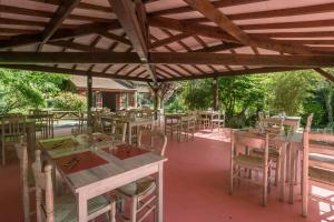 a patio with tables and chairs under a wooden roof at La Cascade Hôtel in Saint-Genis-les-Ollières