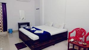 Un dormitorio con una cama y una silla roja. en MALLICK PALACE NEIL Island, en Neil Island