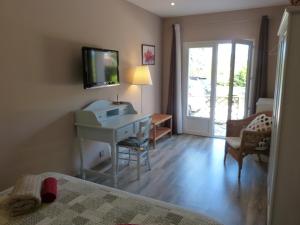 Schlafzimmer mit einem Bett, einem Schreibtisch und einem TV in der Unterkunft Les Tourterelles in Saint-Aygulf