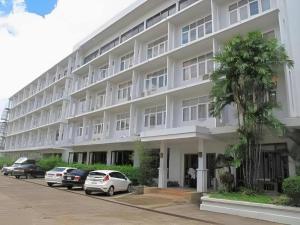 Un gran edificio blanco con coches aparcados delante. en Dusit Hotel, en Sakon Nakhon