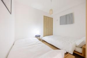 two beds in a bedroom with white walls at Nagoya Hanezu in Nagoya