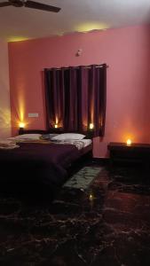 Baada Beach VT stay في Tadri: غرفة نوم بجدران وردية وسرير بستائر أرجوانية