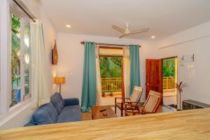 a living room with a blue couch and chairs at Palmera Home Stay in Siolim +4 photos