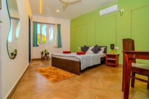 a bedroom with a bed with green walls at Palmera Home Stay in Siolim