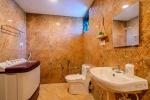 a bathroom with a sink and a toilet and a mirror at Palmera Home Stay in Siolim