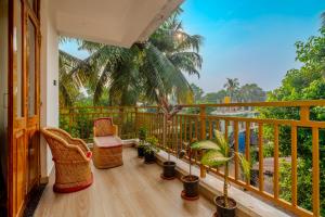 a balcony with chairs and potted plants at Palmera Home Stay in Siolim