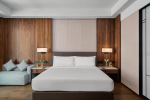 a bedroom with a large white bed and a couch at Crowne Plaza Phnom Penh by IHG in Phnom Penh
