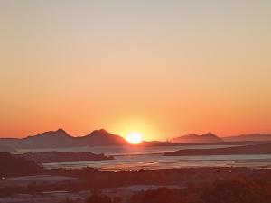 una puesta de sol sobre el océano con montañas en el fondo en The Grays, en Whangarei 6 fotos más