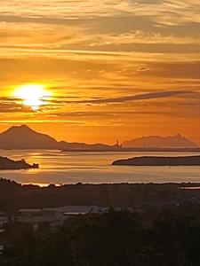 un tramonto sull'acqua con montagne sullo sfondo di The Grays a Whangarei Altre 5 foto