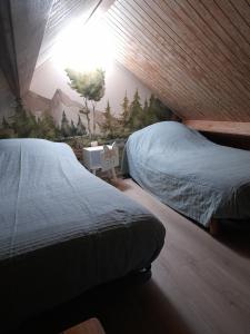 een slaapkamer met 2 bedden en een muur met een muurschildering bij La Longère des Oies in La Celle-sous-Gouzon