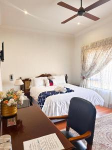a bedroom with a bed and a desk with a chair at Tsheryl's Residence in Centurion