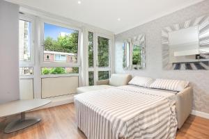 Dormitorio blanco con cama y ventanas en Sach's 2 Bedrooms Apartment - No lift, en Londres