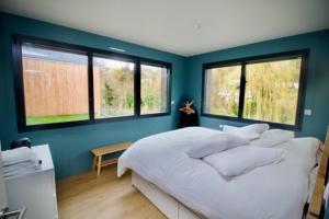 una camera da letto con pareti blu e un ampio letto con cuscini di Confort détente près de la plage - Maison avec jardin et parking privé - Veules-les-Roses a Veules-les-Roses