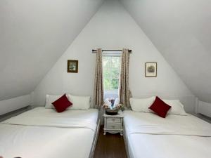 two beds in a attic room with a window at Chermonné House เฌอมอญ in Ban Komo Chet +7 photos