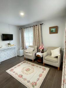 a living room with two chairs and a tv at Chermonné House เฌอมอญ 