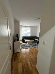 een woonkamer met een zwarte bank en een houten vloer bij Apartman Ranija in Rožaje