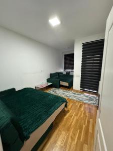 een slaapkamer met een groen bed en een bank bij Apartman Ranija in Rožaje +2 foto's