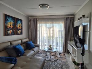 a living room with a couch and a large window at Charming Oasis in the East in Boksburg