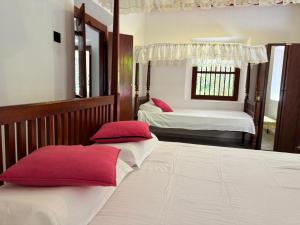 een slaapkamer met 2 bedden en rode kussens bij John's Homestay in Talpe
