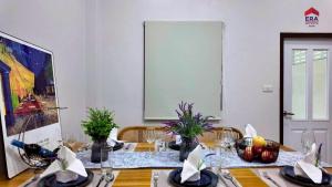 a dining room with a table with chairs and a painting at Aqua pool villa in Ban Nong Thale