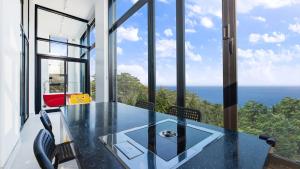 a glass dining room with a table and views of the ocean at Goseong Belossi Ayajin Kids Poolvilla in Goseong +2 photos