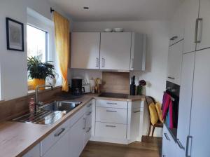 una cucina con mobili bianchi e un lavandino di Caro´s Landblick a Marktleugast Altre 11 foto