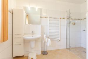 a white bathroom with a sink and a shower at Haus Eichenwald in Glowe +20 photos